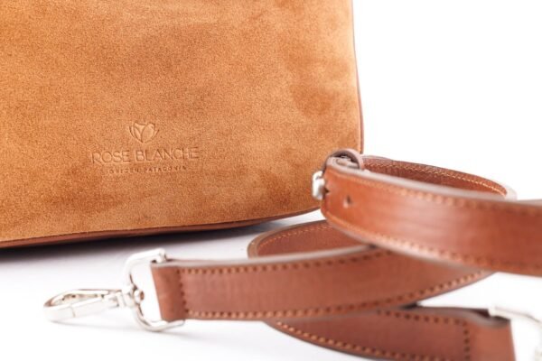 cartera-emma-gamuza-camel-detalle-logo-correa-rose-blanche.jpg Detalle logo Rose Blanche estampado en gamuza camel y correa removible de cuero vacuno, Cartera Emma Patagonia